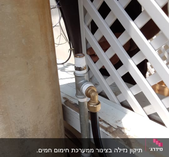 צינור מתכת עם חיבורי פליז ליד מחיצה לבנה